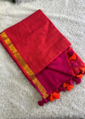 Red and pink saree with orange border and tassels on a white surface