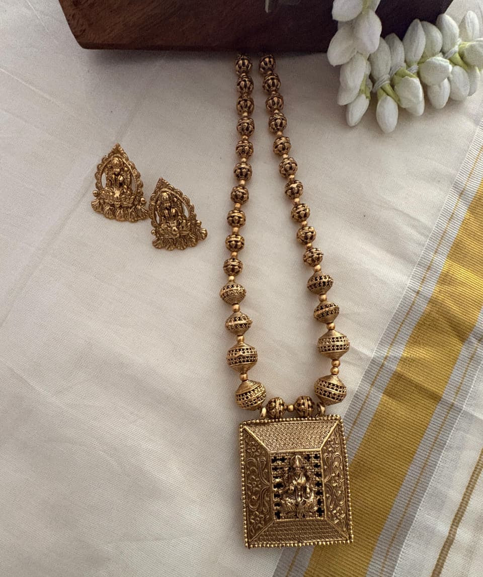 Gold necklace and earrings on a white fabric background