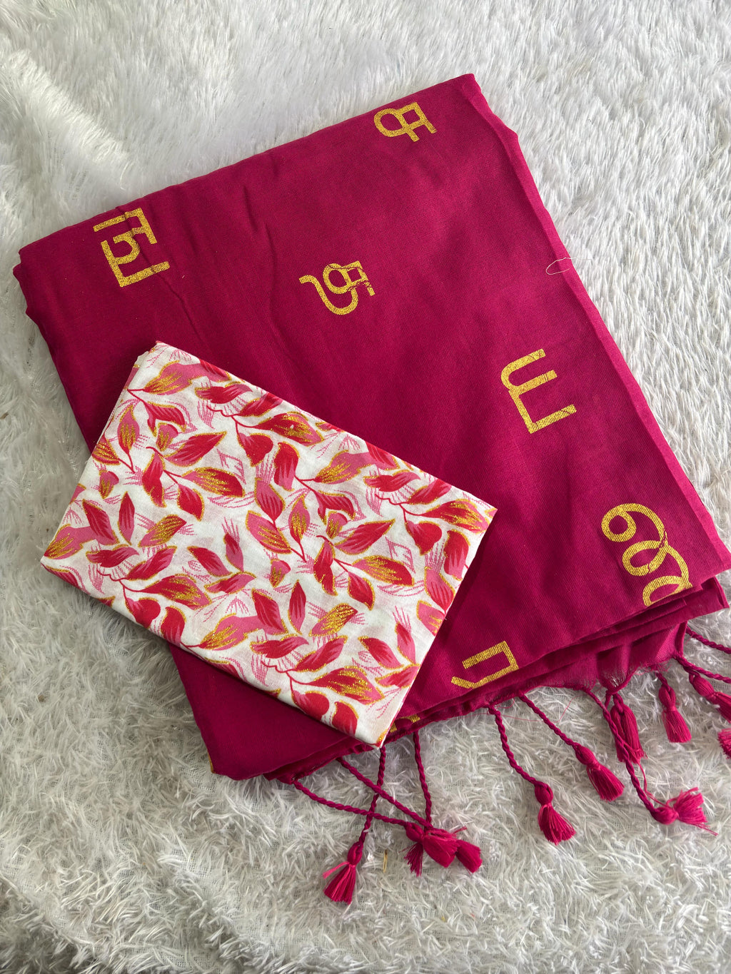 Red scarf with gold patterns and a floral-patterned pouch on a white surface