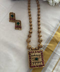 Gold necklace with pendant and matching earrings on a white fabric background